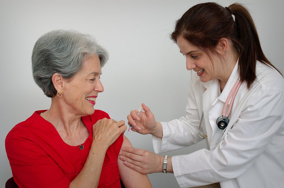 A senior woman receiving a vaccination shot from her doctor : Free Stock Photo