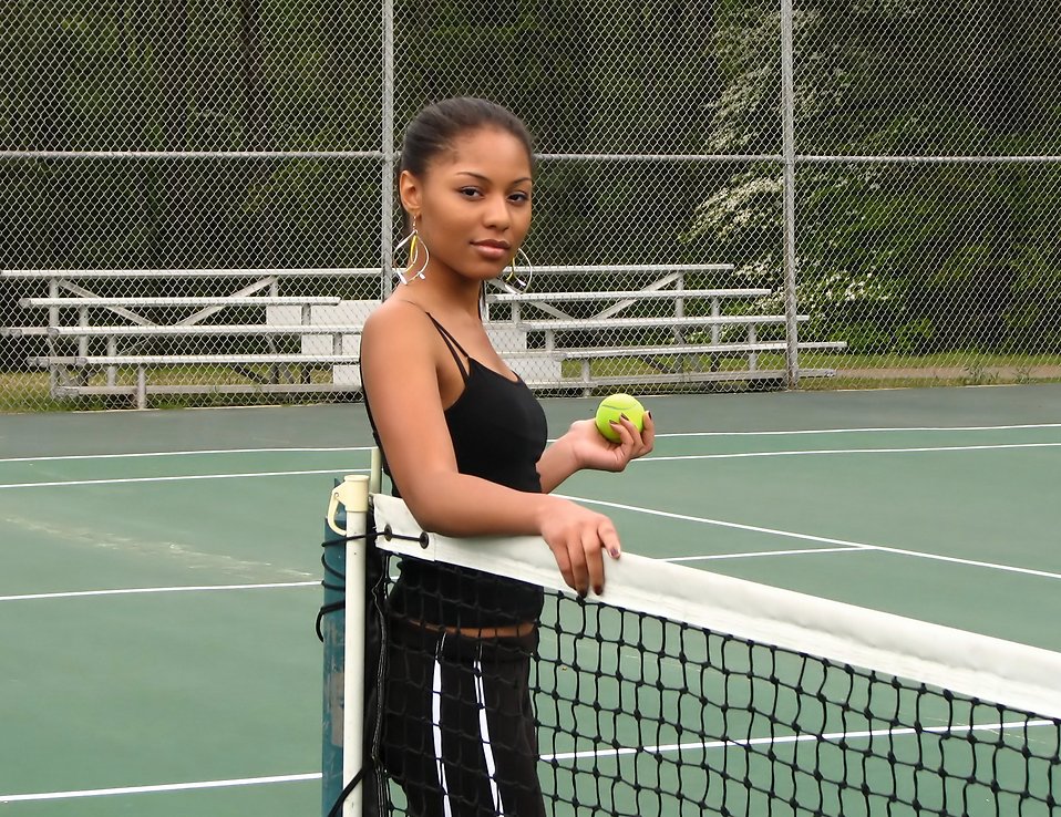 A beautiful African American teen girl on an tennis court with a tennis ball : Free Stock Photo