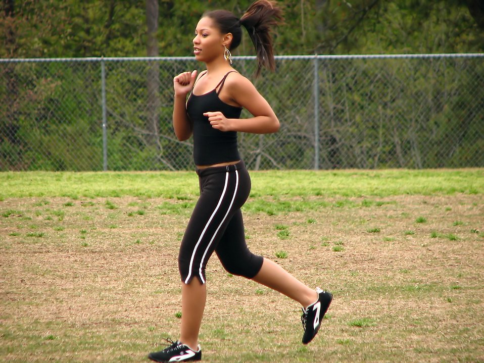 A beautiful teen African American girl running by a fence : Free Stock Photo