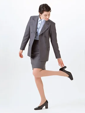 Free Stock Photo: A beautiful woman in a business suit fixing her heel isolated on a white background
