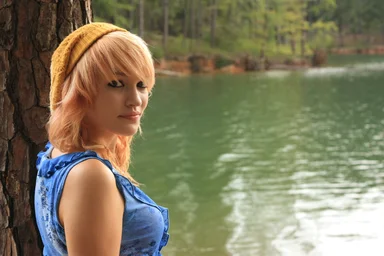 Free Stock Photo: A beautiful young woman posing against a tree by a lake