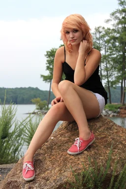 Free Stock Photo: A beautiful young woman posing on a rock by a lake