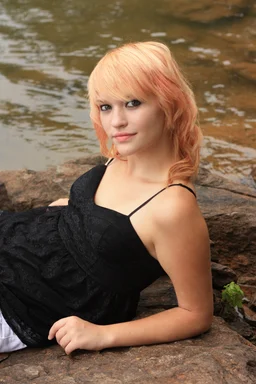 Free Stock Photo: A beautiful young woman posing on a rock by a lake