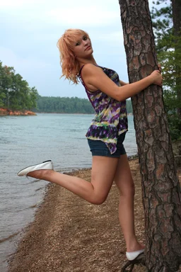 Free Stock Photo: A beautiful young woman posing against a tree by a lake