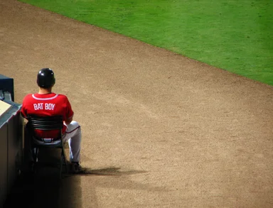 Free Stock Photo: A baseball bat boy sitting on the sideline