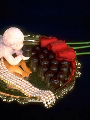 Free Stock Photo: A tray of red rose and chocolate candy with a cupid statue