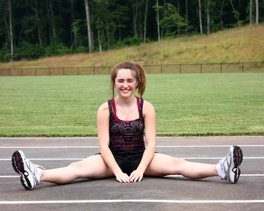 Free Stock Photo: A cute young girl doing stretches on a track field