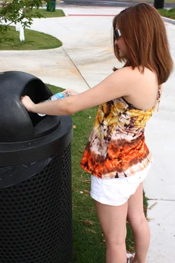 Free Stock Photo: A young girl throwing away trash in a trash can