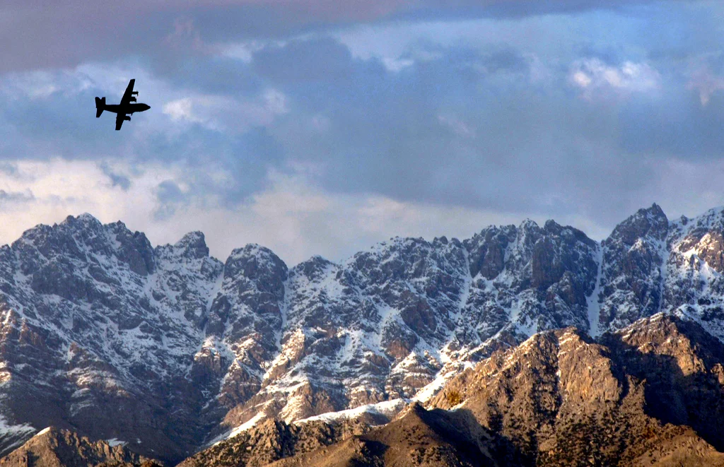 A military airplane flying over mountains : Free Stock Photo