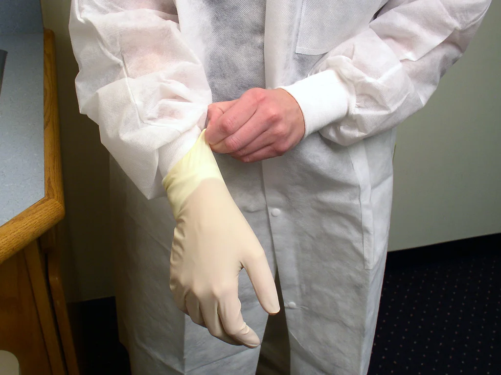A lab technician putting on disposable gloves : Free Stock Photo