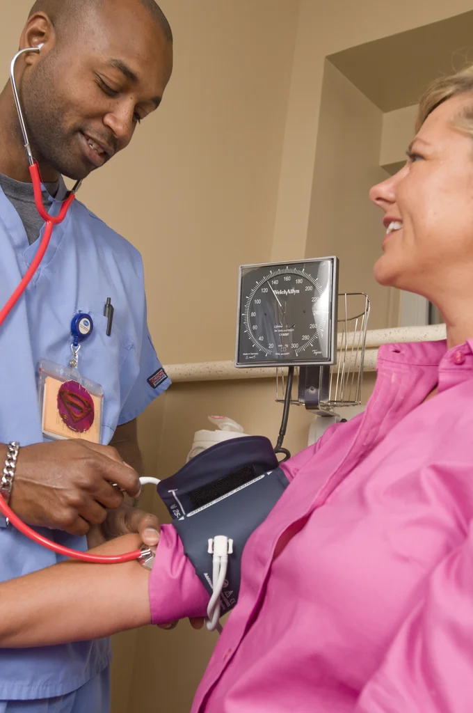 A male nurse taking the blood pressure of a woman : Free Stock Photo