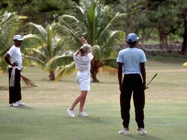 Free Stock Photo: A woman swinging a golf club on tropical course