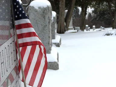Free Stock Photo: Closeup of a US flag and tombstone in a snow covered graveyard
