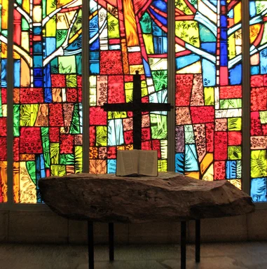 Free Stock Photo: A small cross and a bible in front of a stained glass window