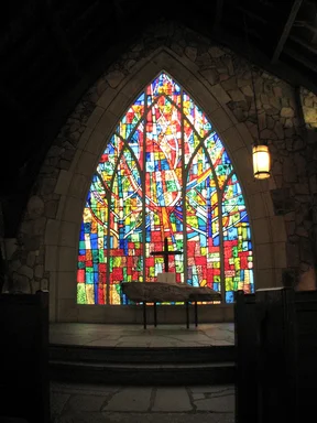 Free Stock Photo: A small cross in front of a stained glass window