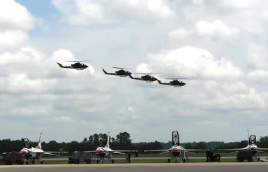 Free Stock Photo: AH-1F Cobra attack helicopters flying over a runway with Thunderbird jets