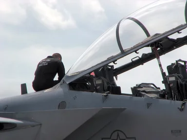Free Stock Photo: A maintenance crew member sitting on an F-18 fighter jet