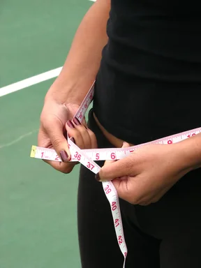 Free Stock Photo: A beautiful teen African American girl measuring her waist with a tape measure