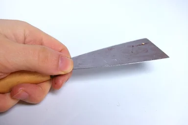 Free Stock Photo: A hand holding a putty knife isolated on a white background