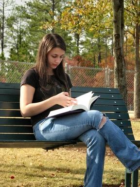 Free Stock Photo: Teenage girl reading a book on a bench