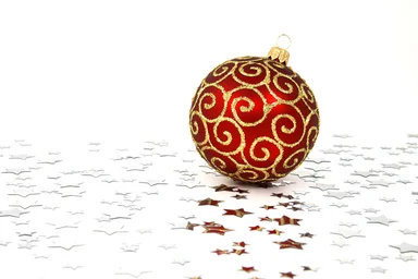 Free Stock Photo: A red Christmas ornament on a white floor with silver stars