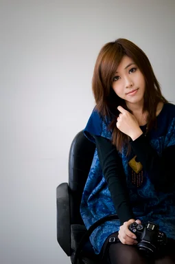Free Stock Photo: A beautiful Chinese girl posing in a chair with a camera