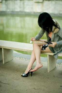 Free Stock Photo: A beautiful Chinese girl sitting on a bench fixing her shoe